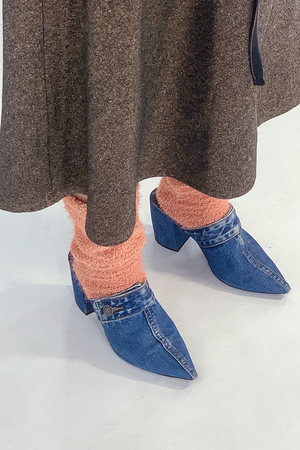 women's feet wearing coral orange fuzzy socks, paired with blue denim heels and a long brown skirt