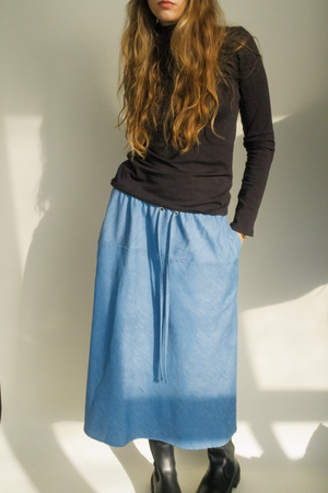A stylish and fashionable woman wearing a long blue denim viscose skirt paired with a long black turtleneck. This outfit is both comfortable and trendy, perfect for any occasion. made in Montreal.