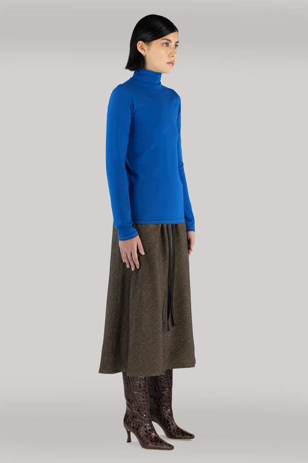 woman standing with cobalt blue turtleneck long sleeve and long maxi brown wool skirt and maroon boots
